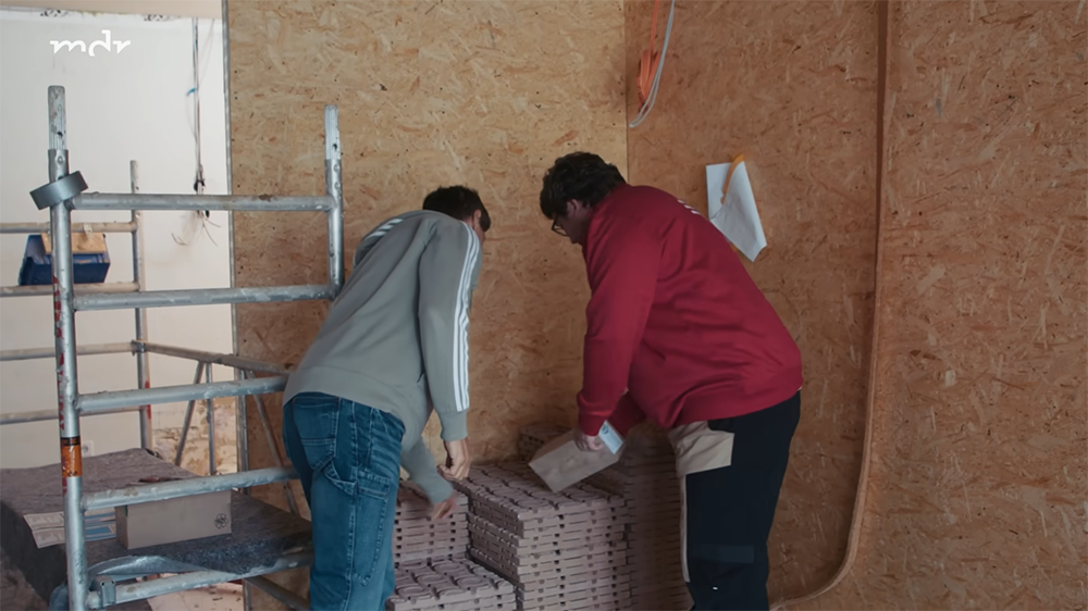 Herr Lange und Handwerker über Palette mit HUMID-Modulen gebeugt